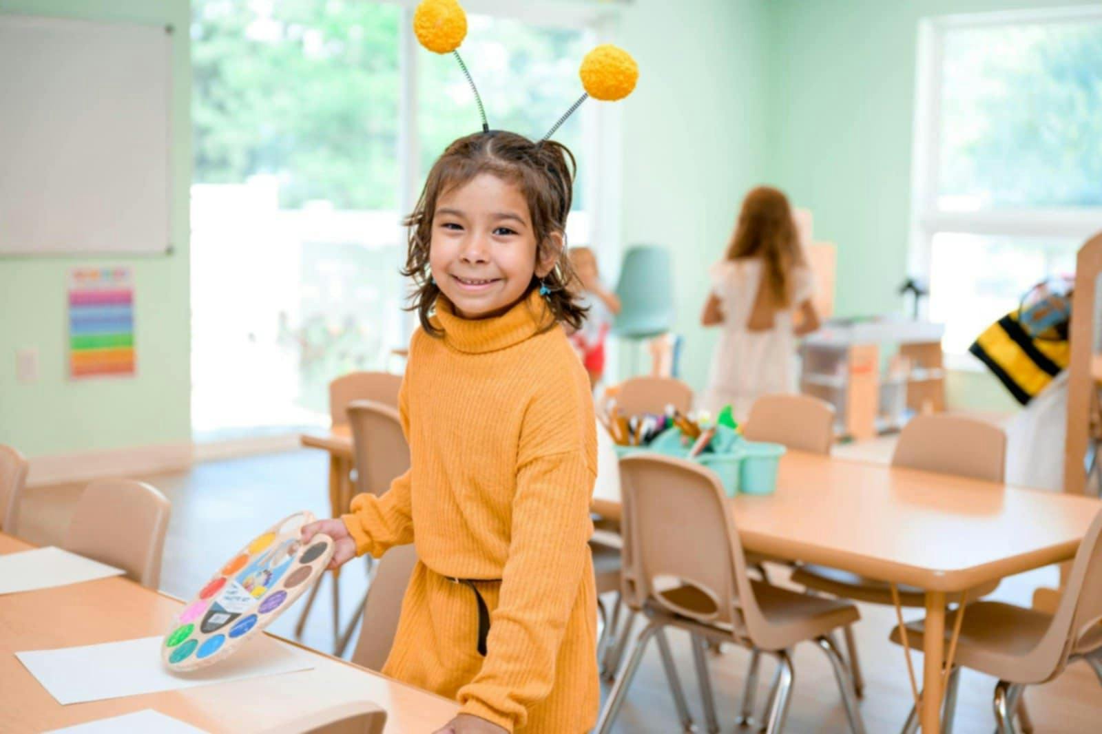 Child in a classroom holding a paint palette