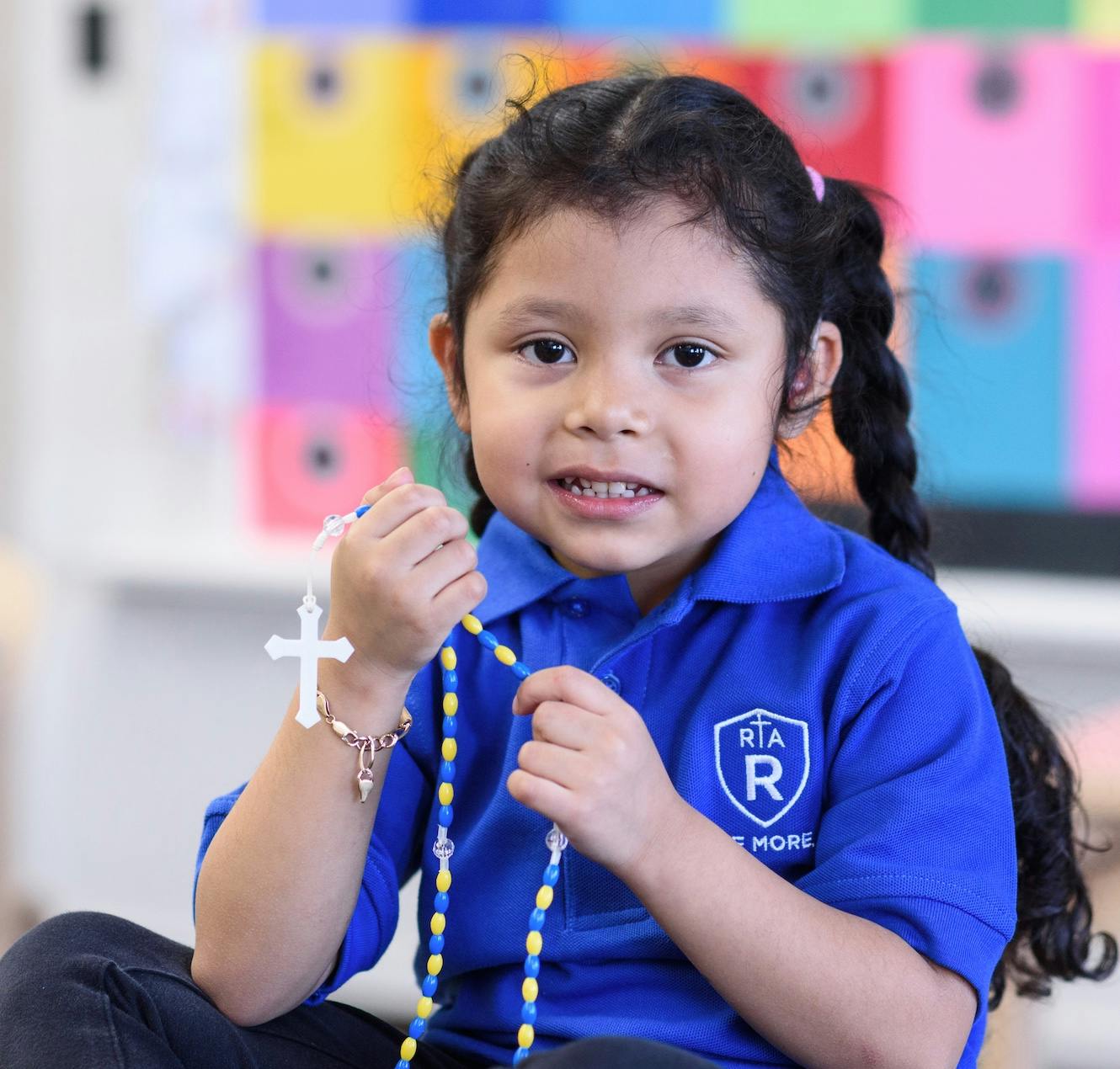 Child in blue shirt holding a rosary