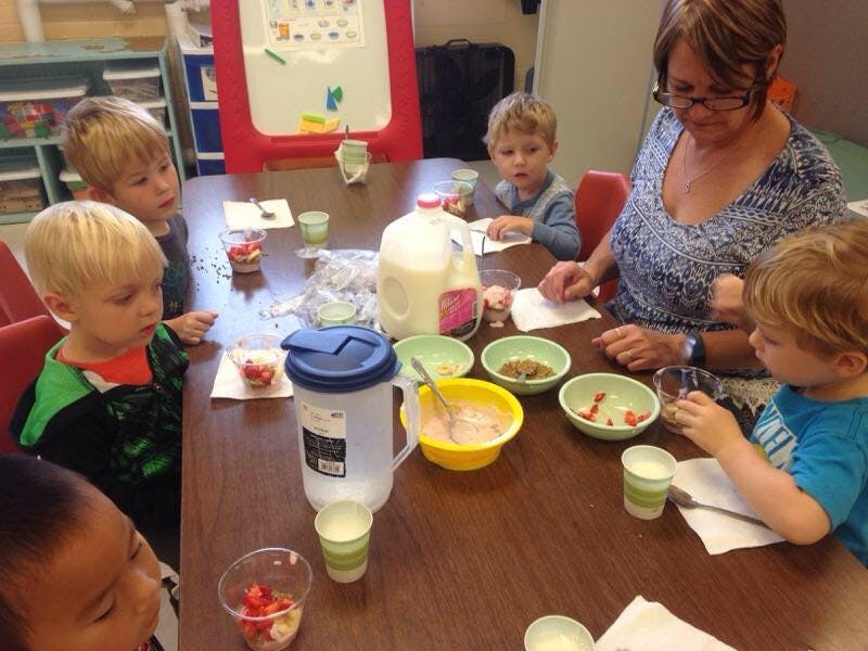 Adult and children sitting at a table with bowls and drinks