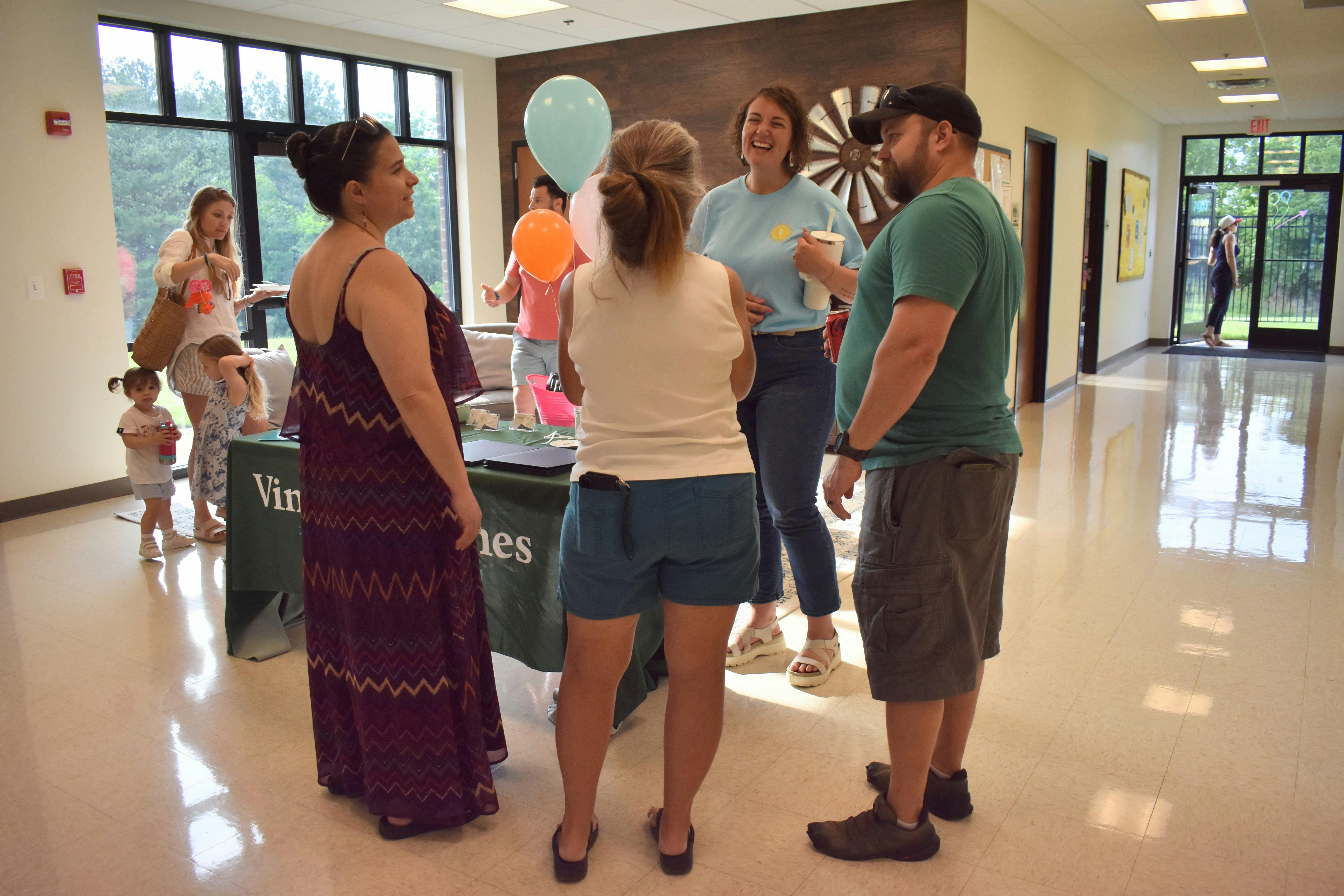 Group of adults and children standing near a table with balloons