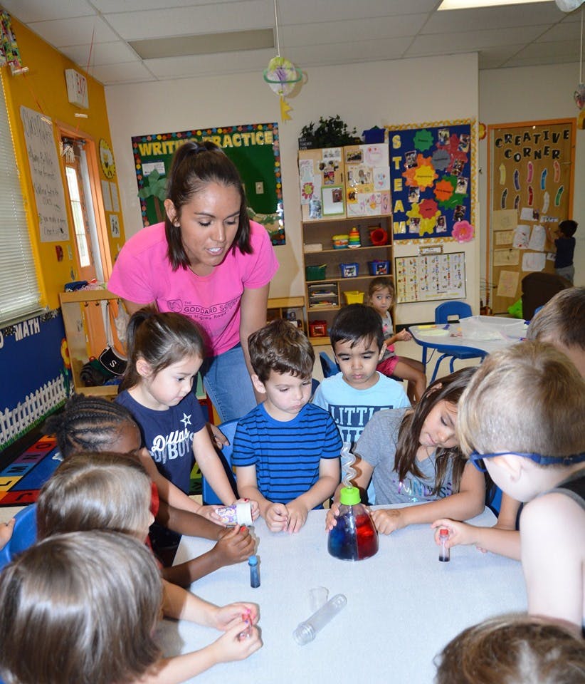 Adult and children gathered around a table with science experiment materials