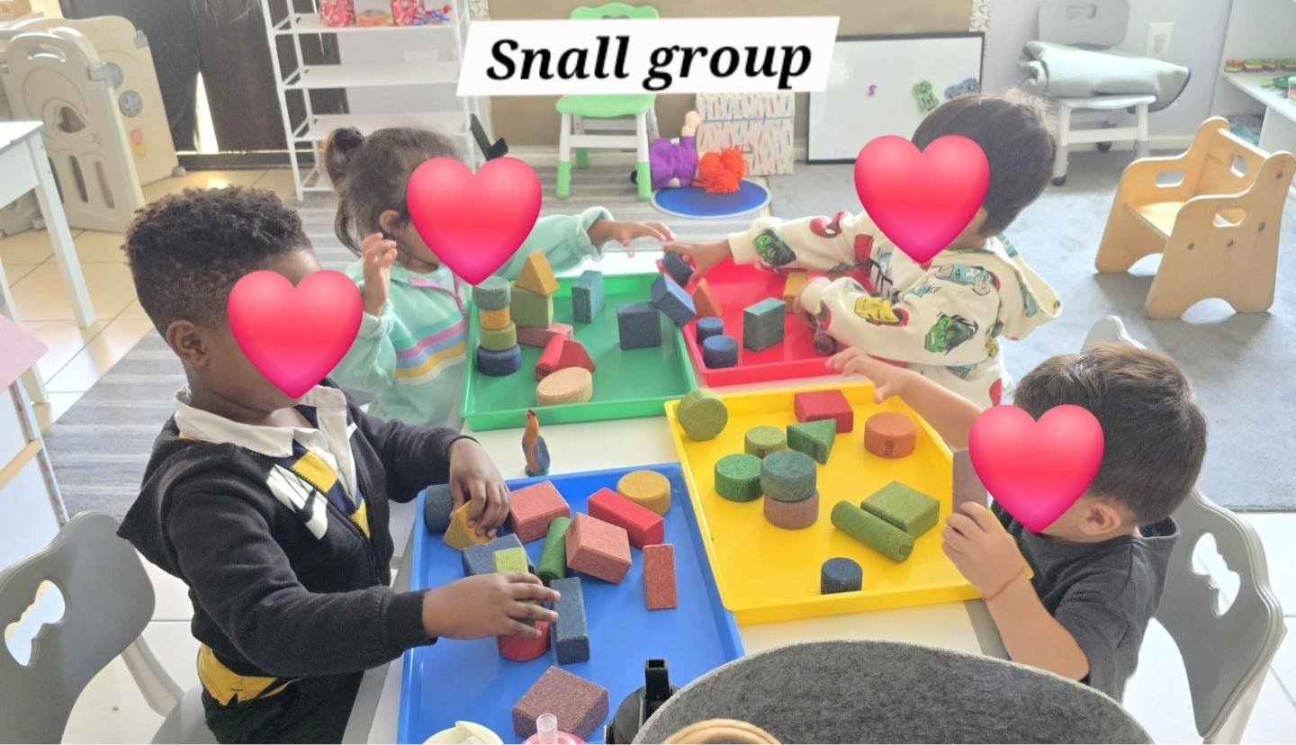Children playing with colorful blocks at small group tables in a classroom