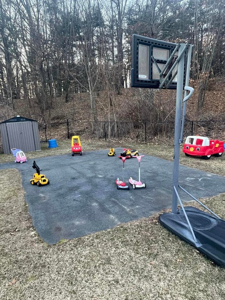 Basketball hoop and children's ride-on toys on an asphalt pad