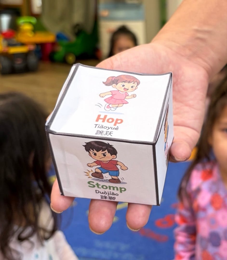 Hand holding a paper cube featuring illustrations labeled Hop and Stomp