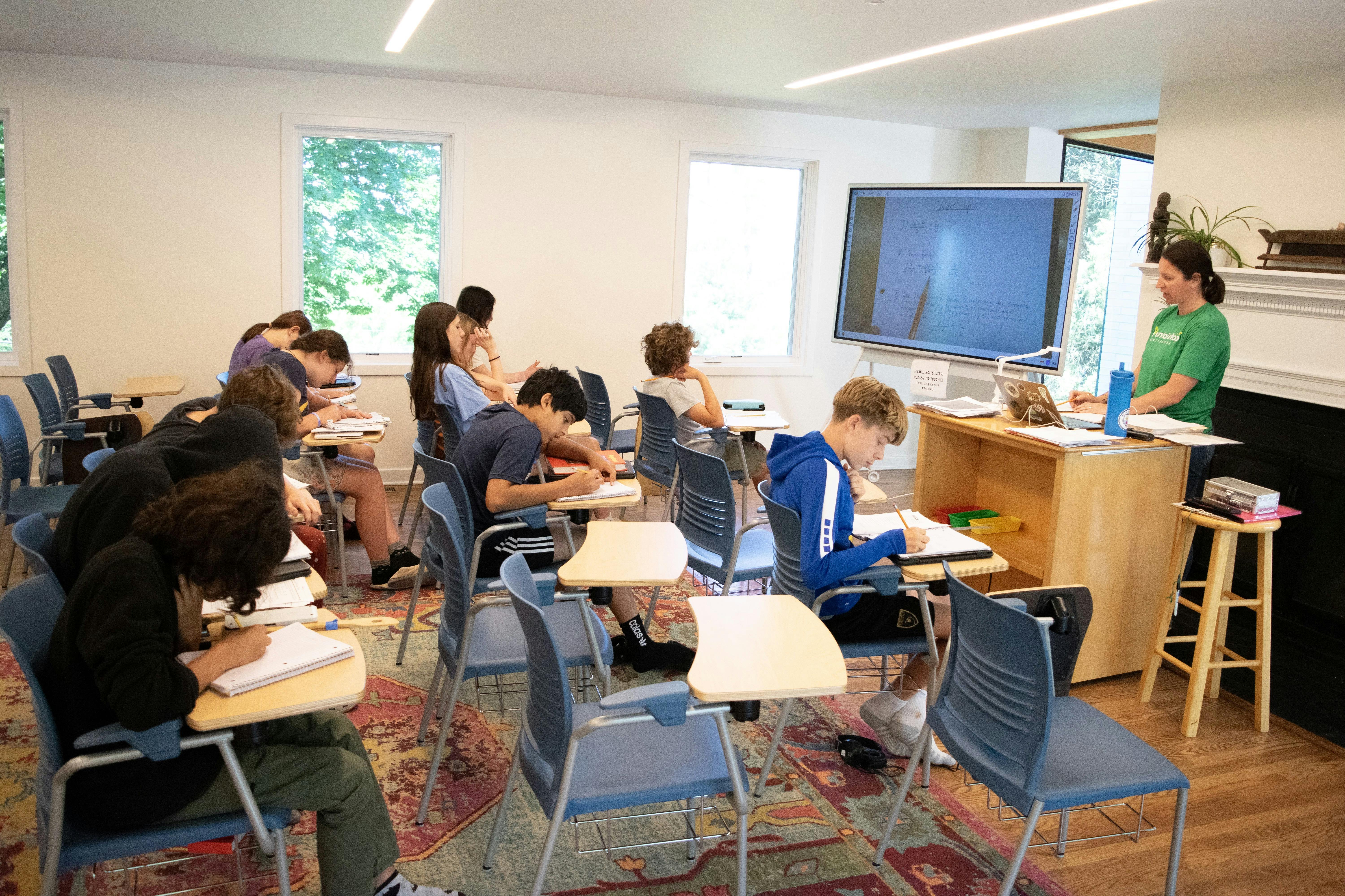People in a classroom writing at desks with an instructor at the front