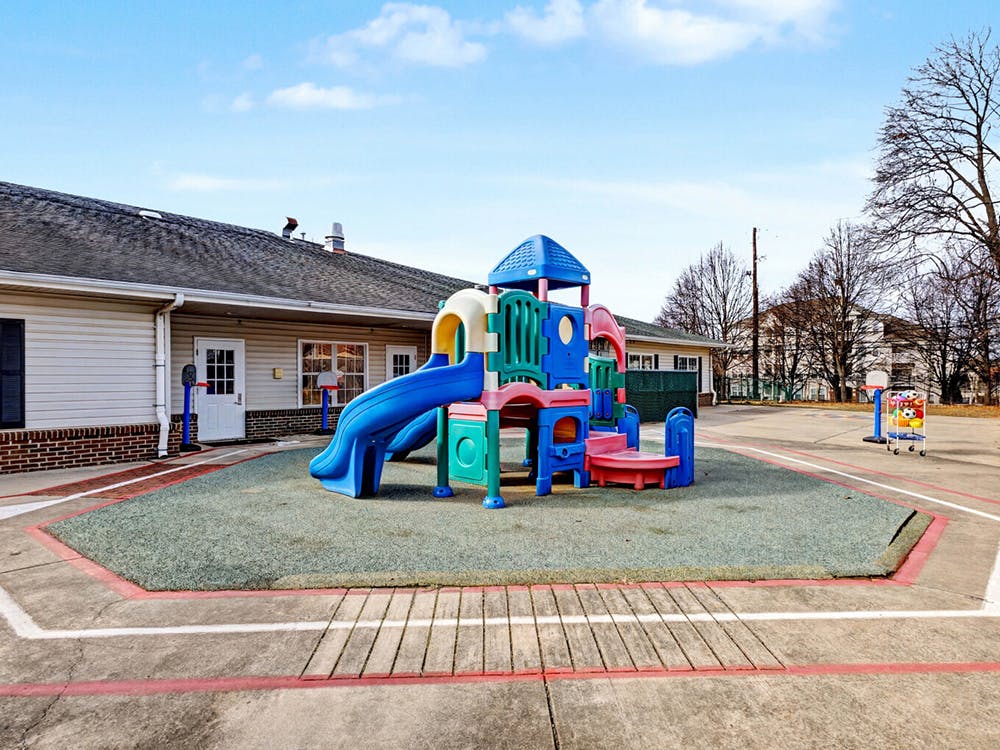 Colorful playground structure on soft ground next to a building