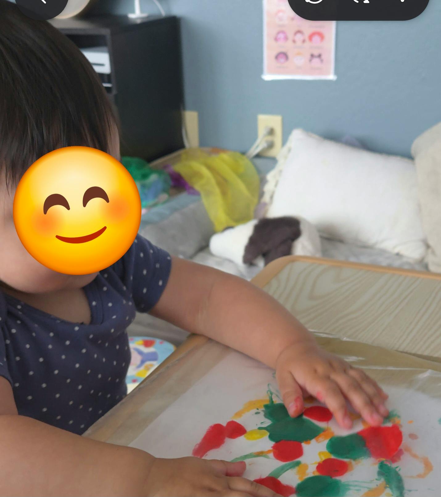 Child painting with fingers on paper at a small table