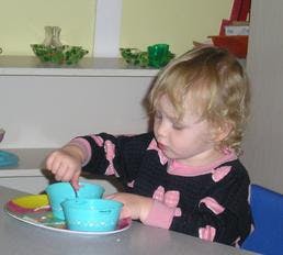 Child playing with small blue bowls on a tray