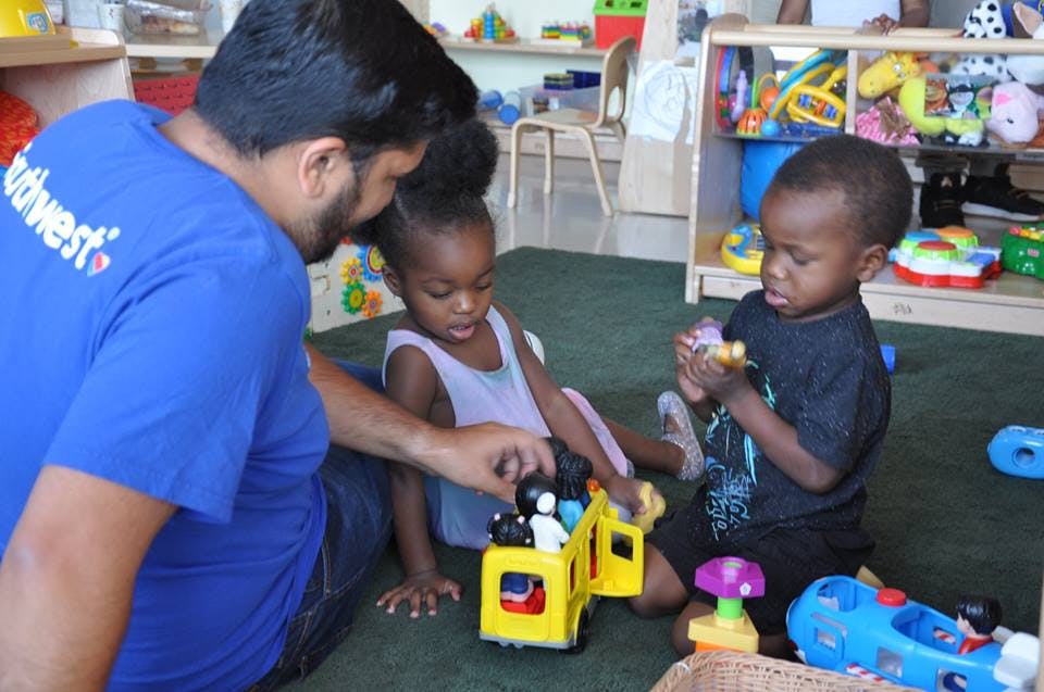 Person and two children playing with toys on the floor