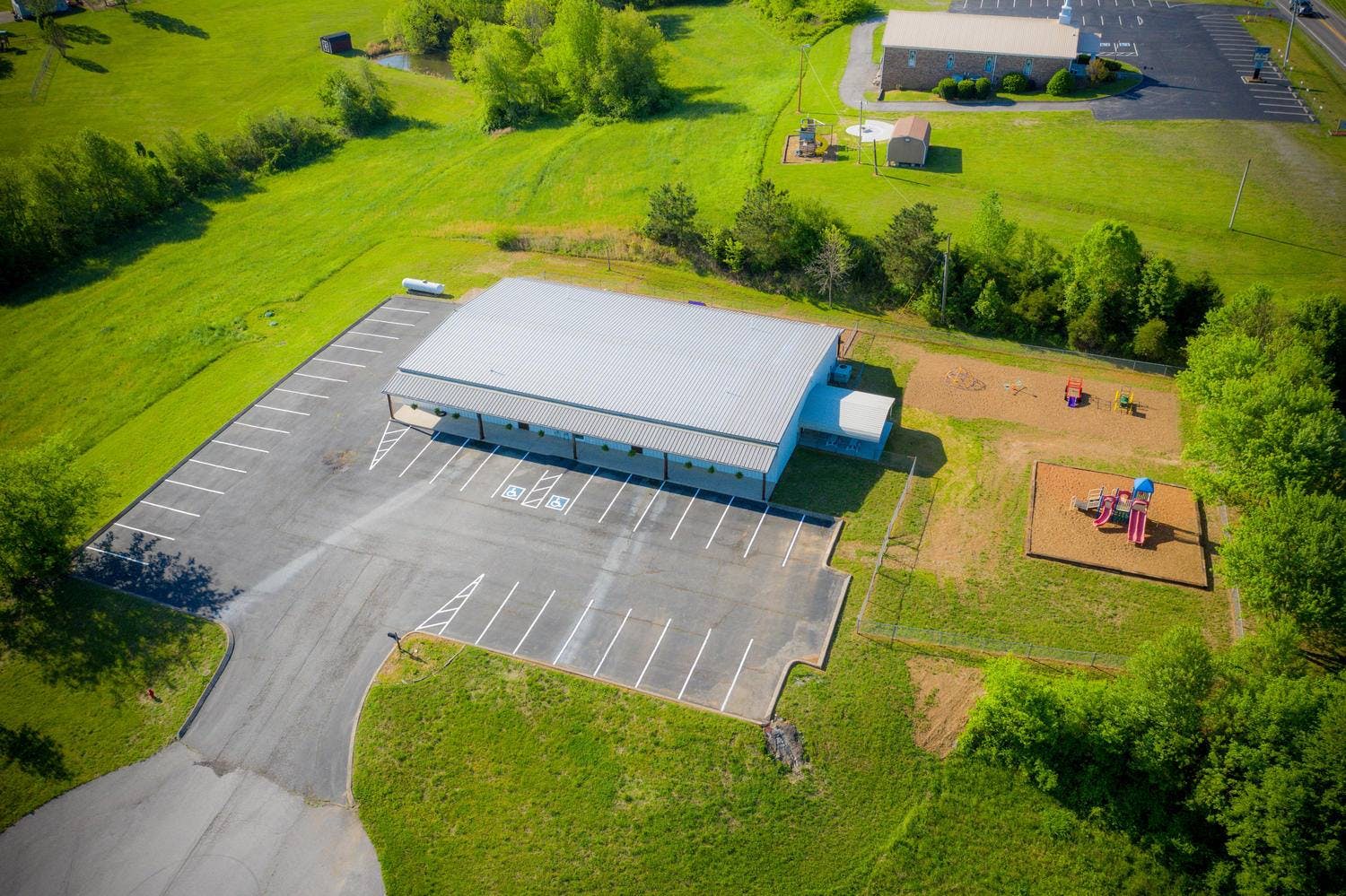 Aerial view of a metal building with a parking lot and playground