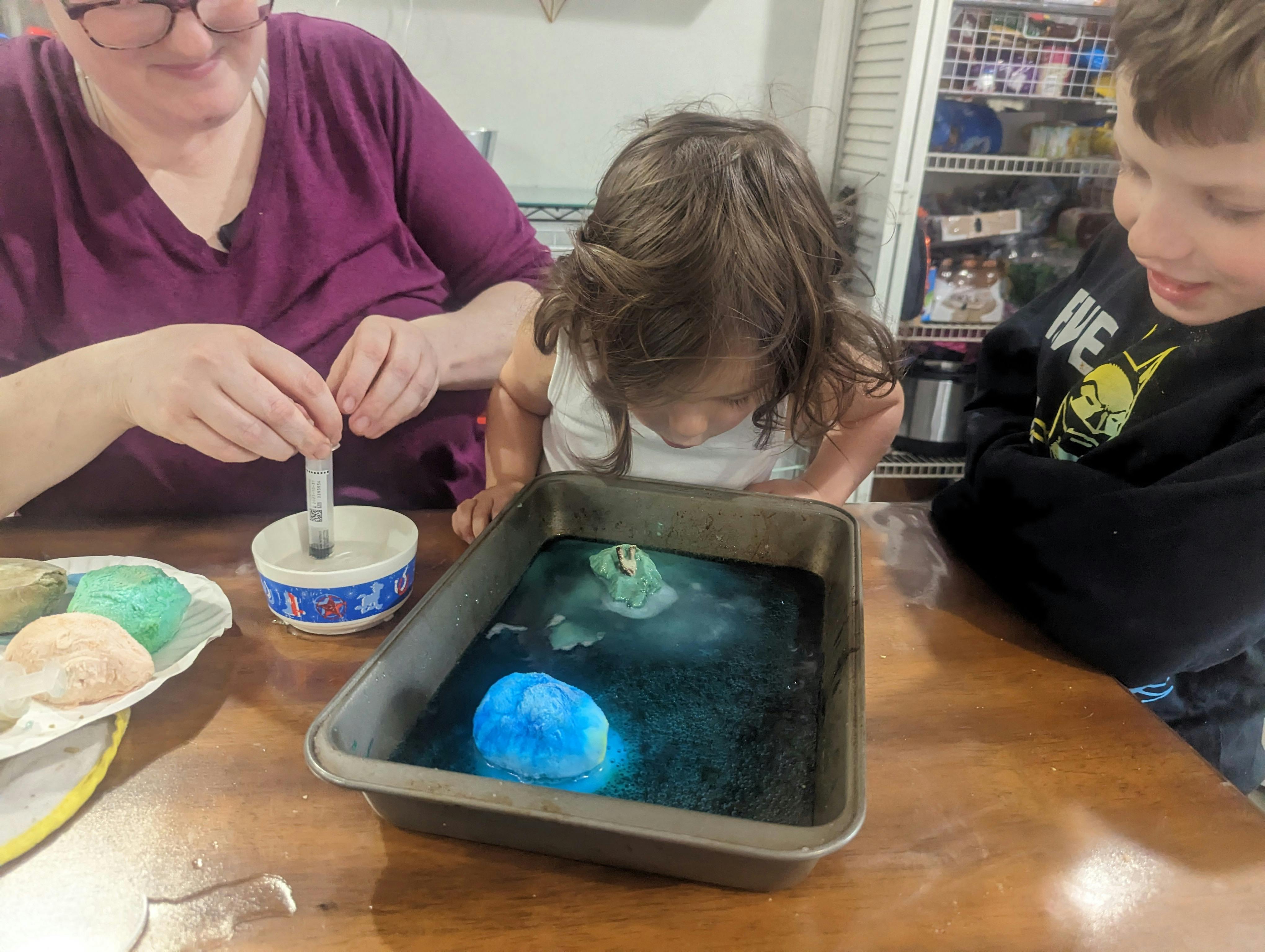 Person and two children doing a science experiment with a pan of baking pan