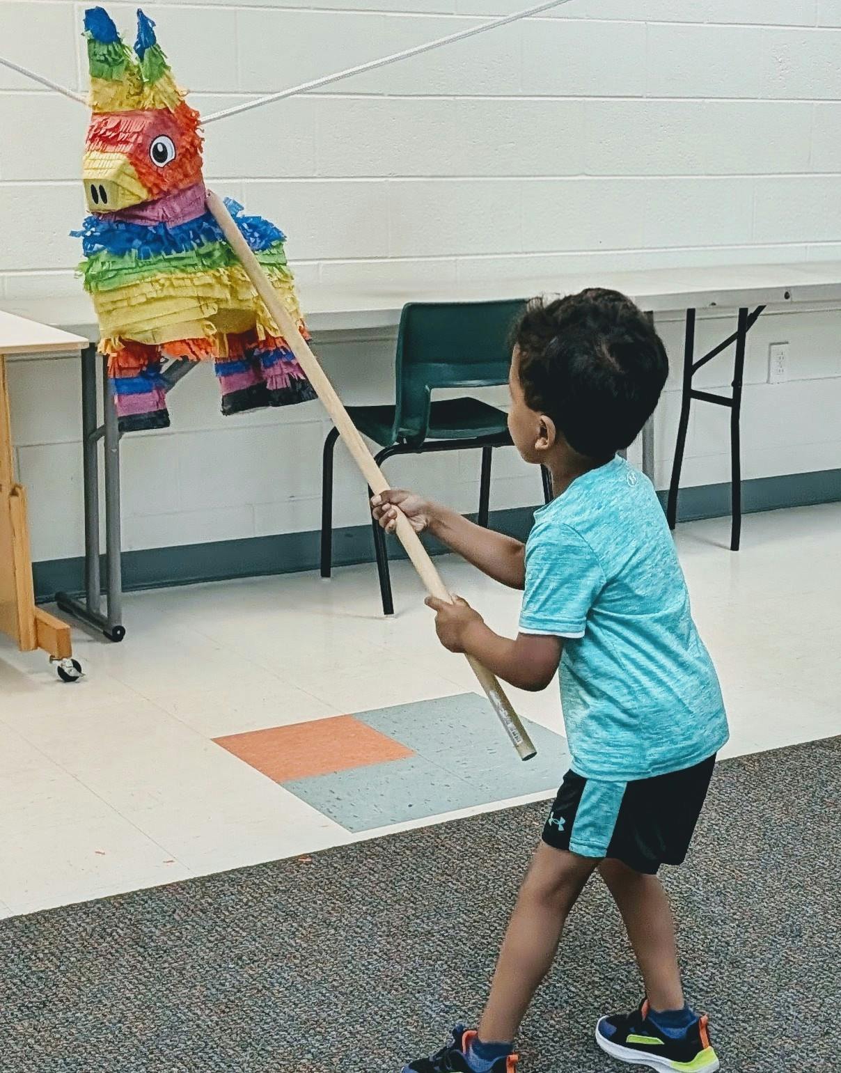 Child hitting a colorful donkey piñata with a stick