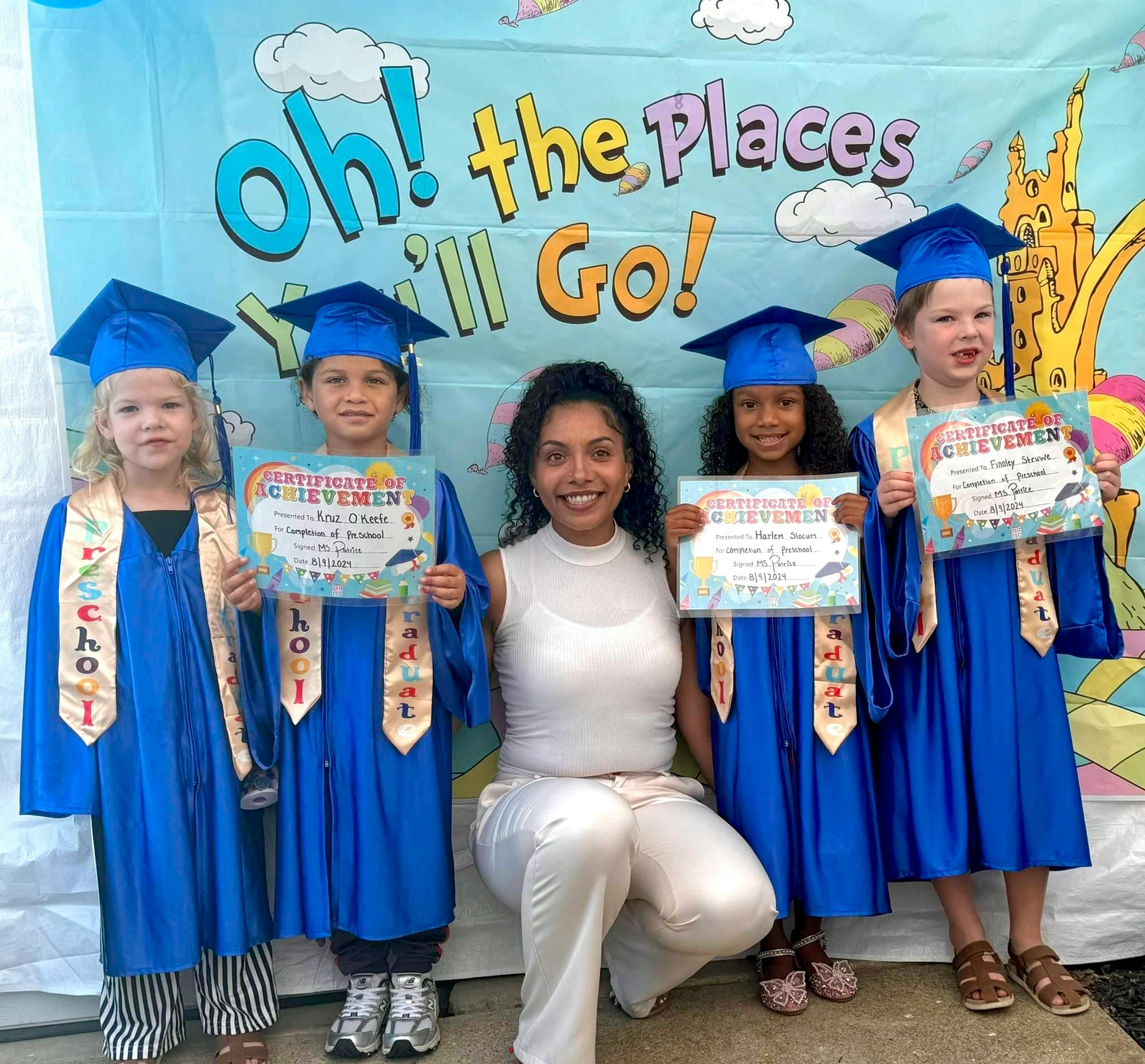 Adult and four children in graduation caps and gowns holding certificates