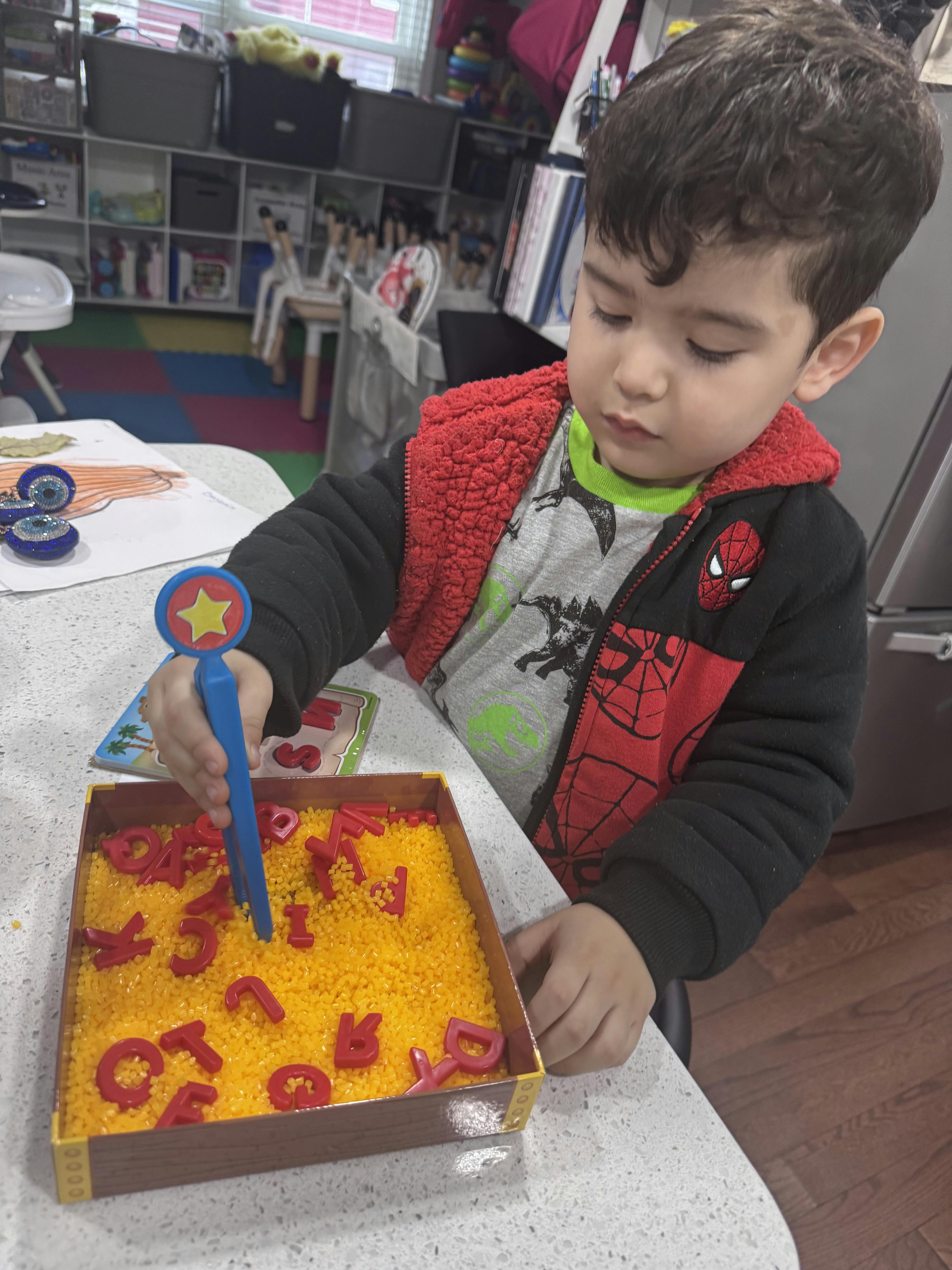 Child playing with letters in a yellow sensory bin