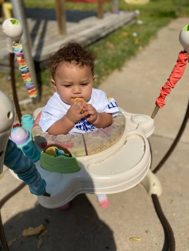 Child in a baby bouncer eating a snack