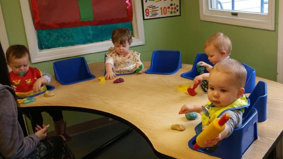 Four children sitting at a table with toys