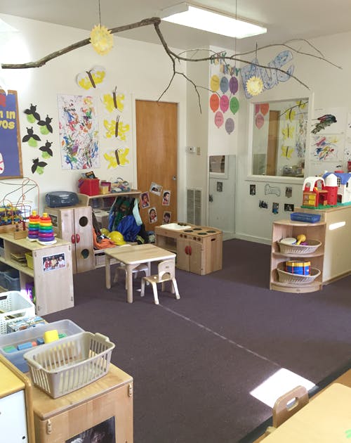 Empty classroom with small tables, chairs, and toys