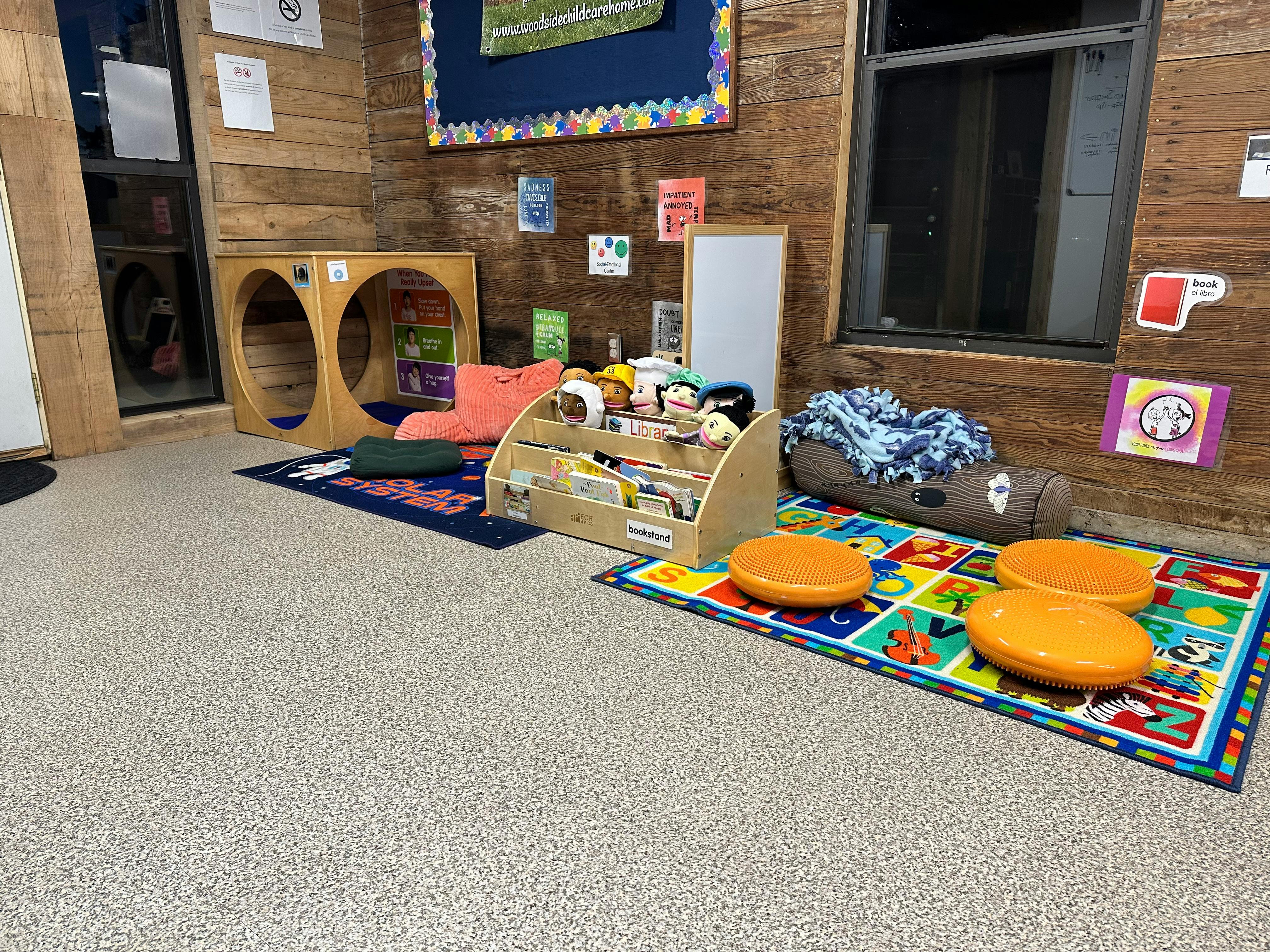 Children's play area with wooden furniture, colorful rugs, and cushions