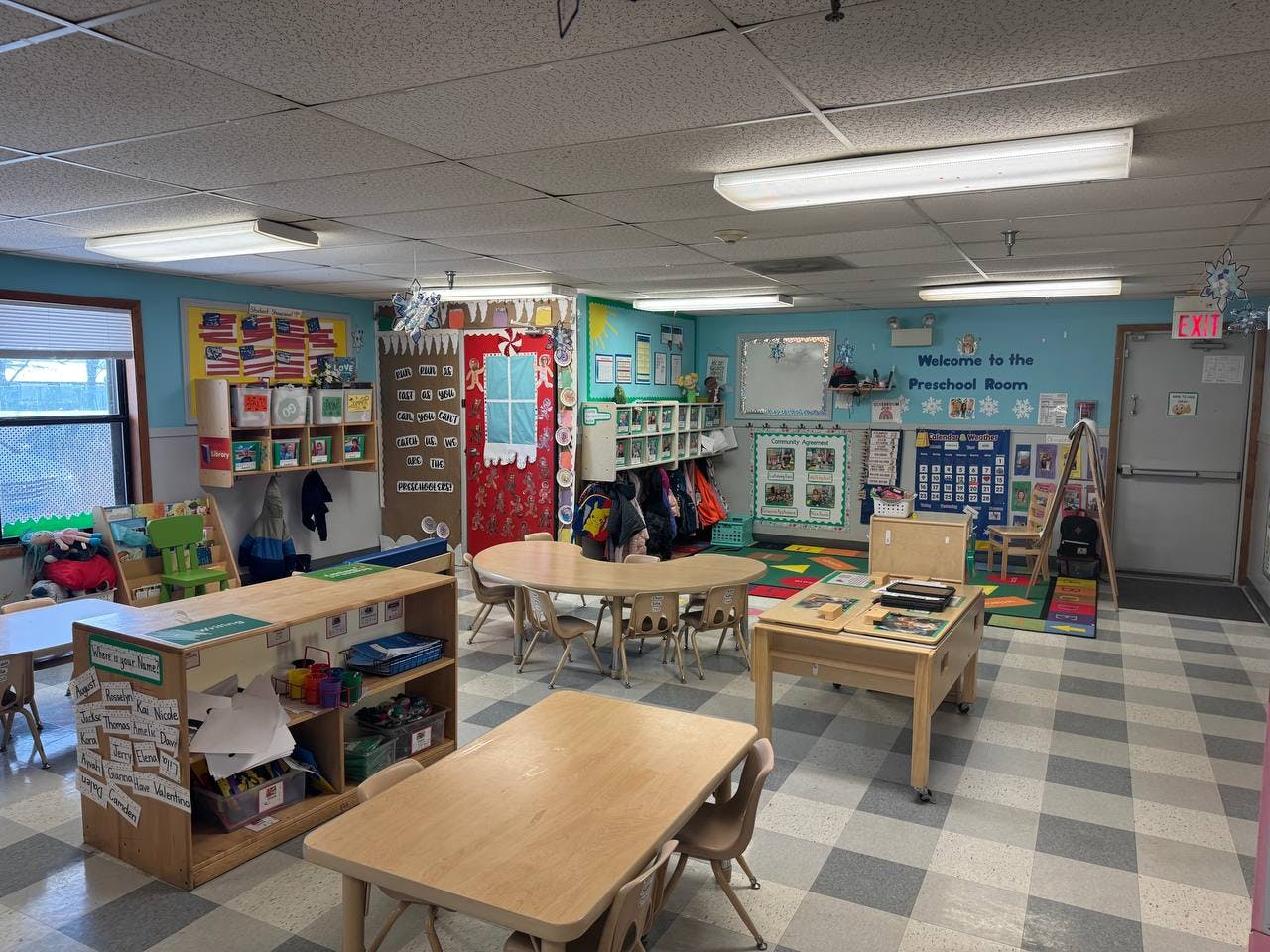Empty preschool classroom with small tables and chairs