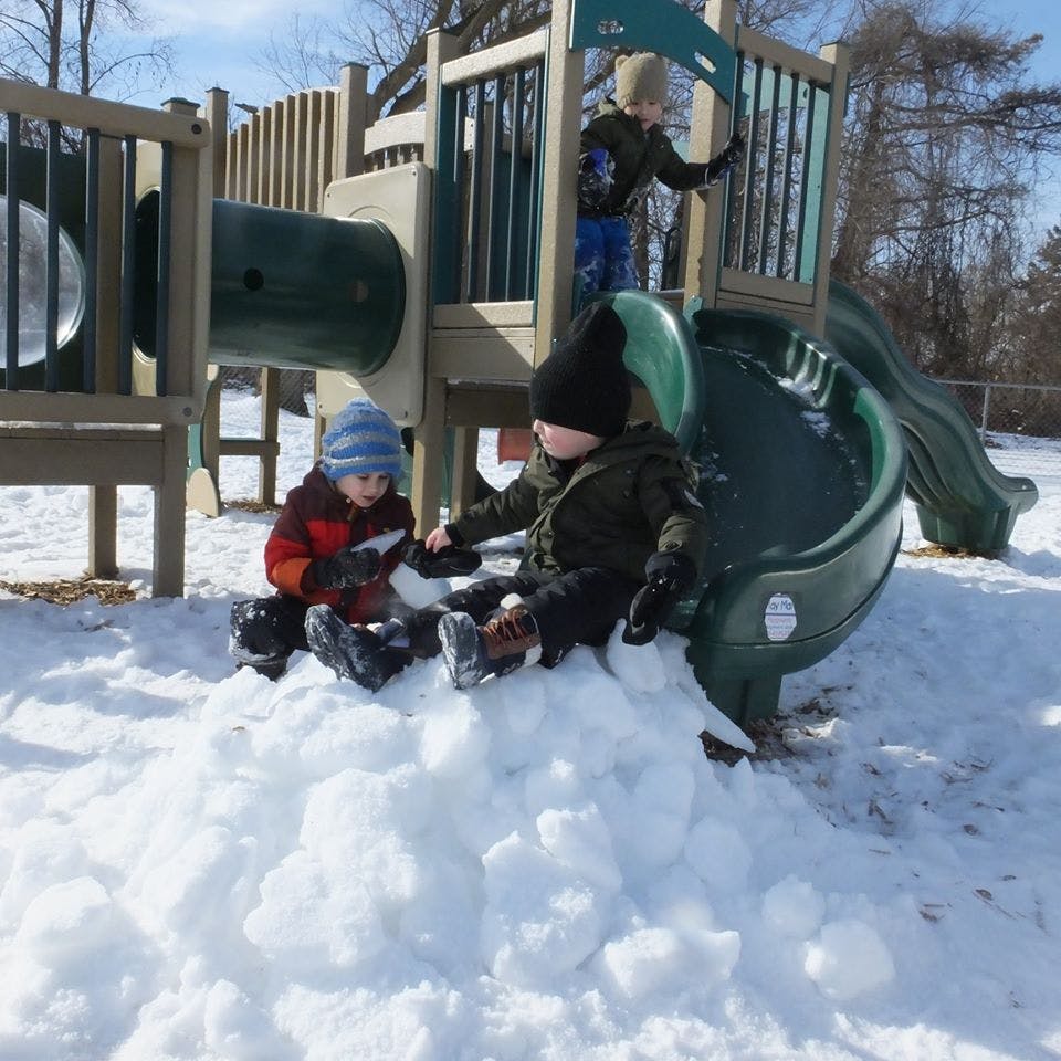 Children playing in snow on a playground
