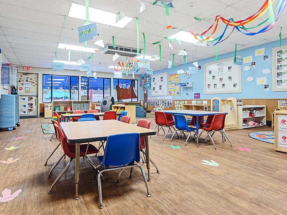 Classroom with small tables and chairs, artwork on walls and hanging from ceiling