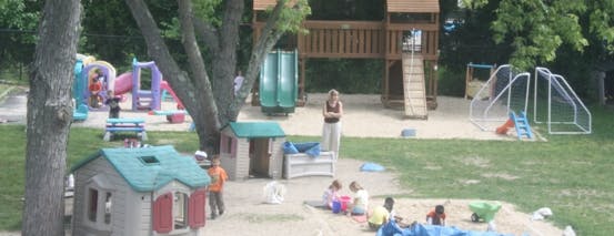Outdoor playground with playhouses, slides, and children playing