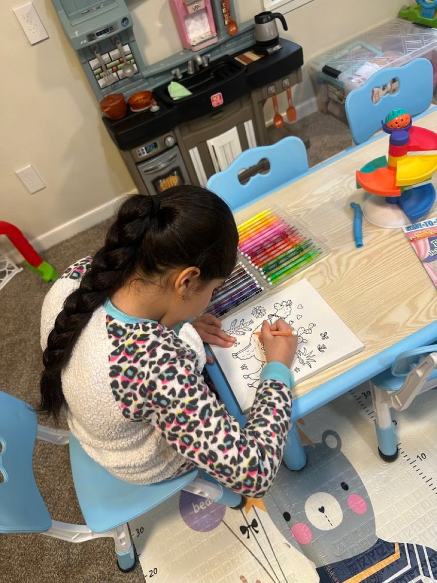 Child coloring in a book at a small table