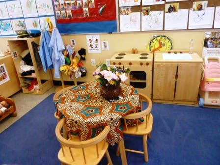 Playroom with small table and chairs, toy kitchen, and coat rack