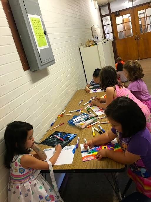 Children drawing and coloring at a long table