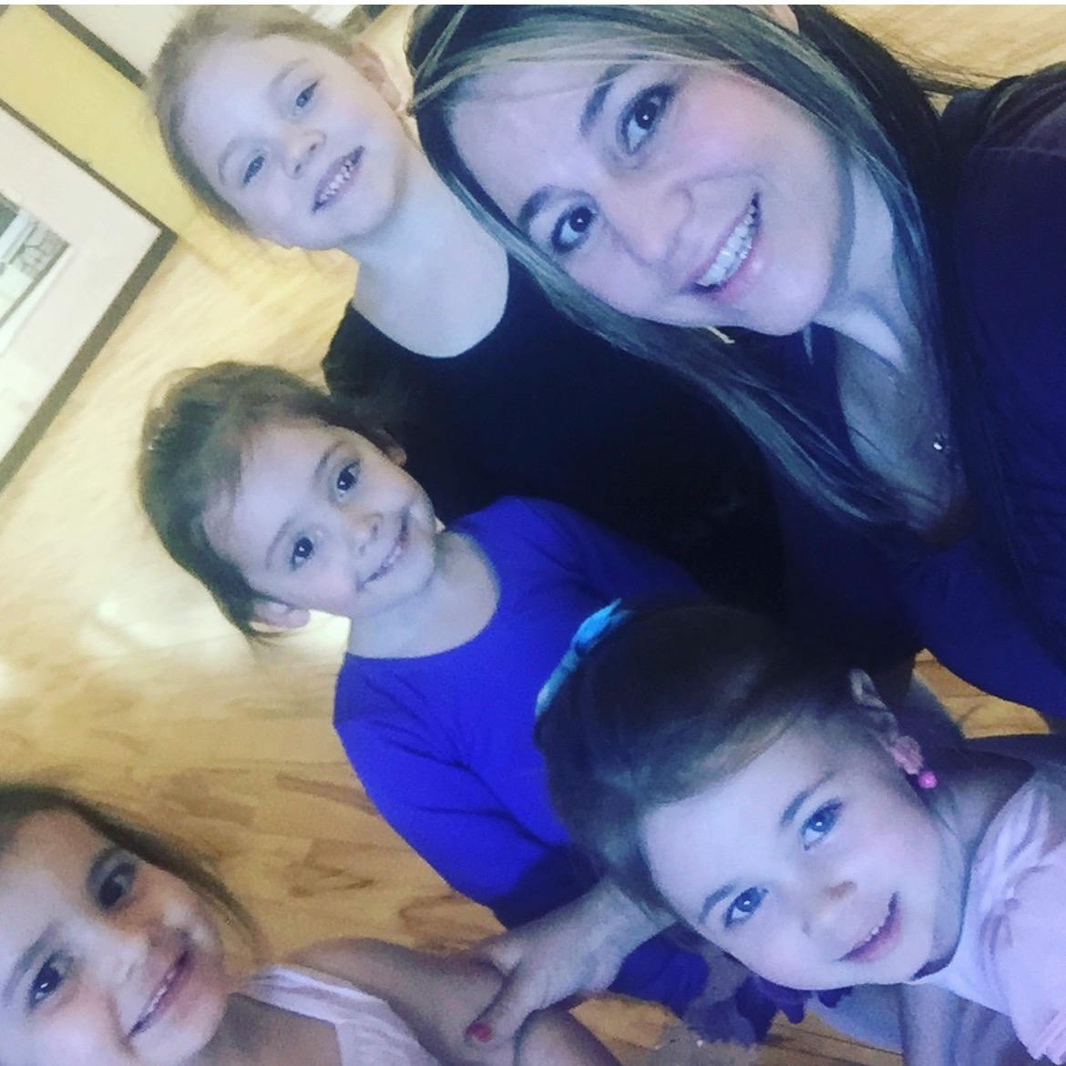 A woman and three young children smiling