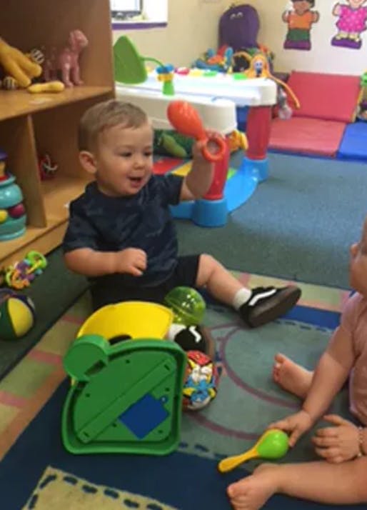 Child holding a red toy in a play area