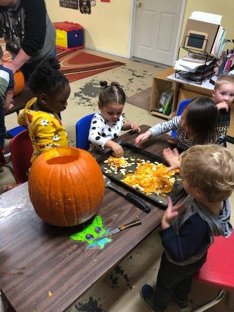 Children carving a pumpkin and removing seeds