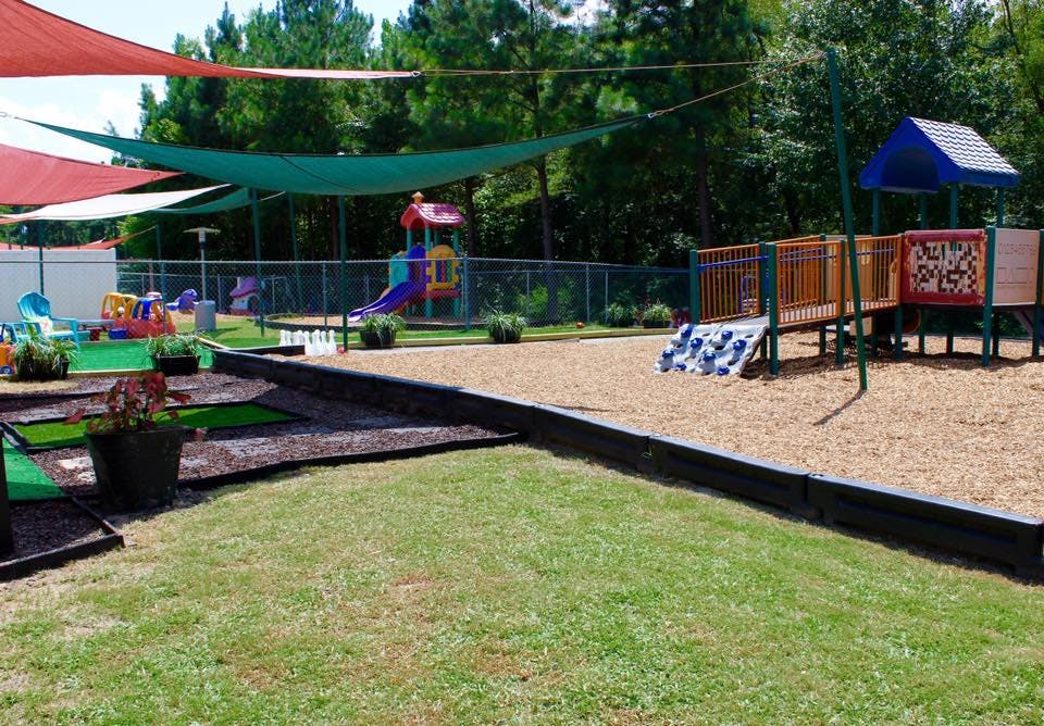 Outdoor playground with play structures, sand, and grass