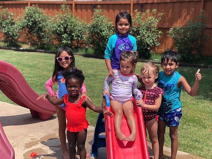 Group of children in swimsuits standing around a red slide