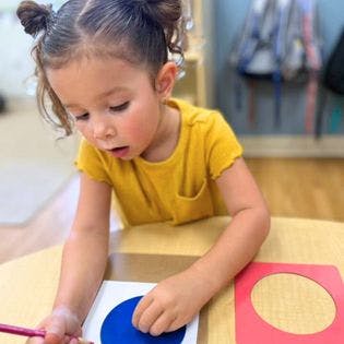 Child drawing with a pencil and a blue circle template