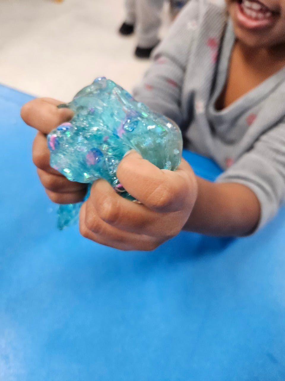 Child's hands holding blue glitter slime