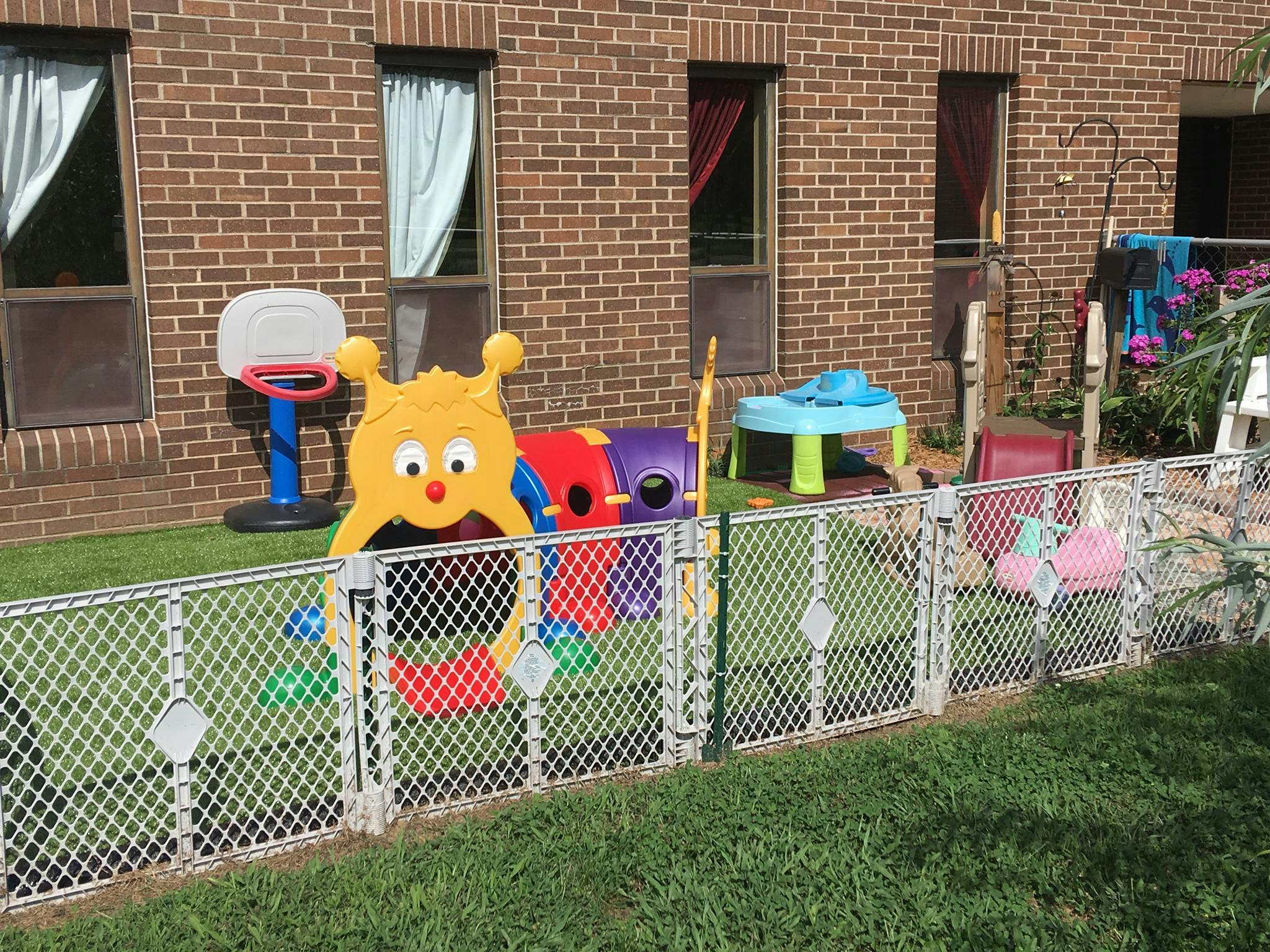 Playground with colorful plastic toys and a chain link fence