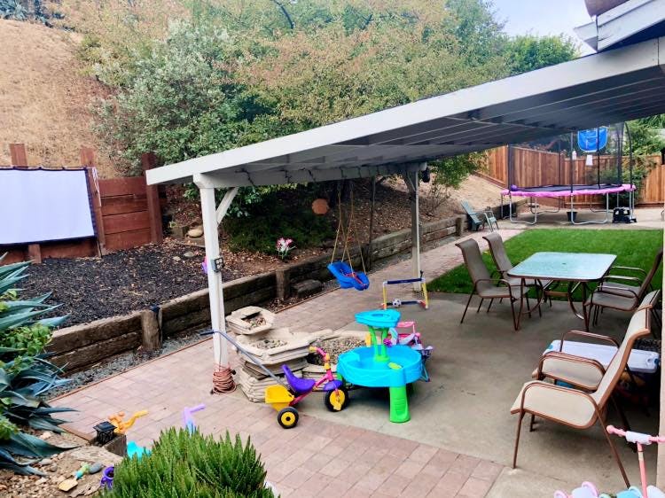 Backyard patio with outdoor furniture, children's toys, and swings