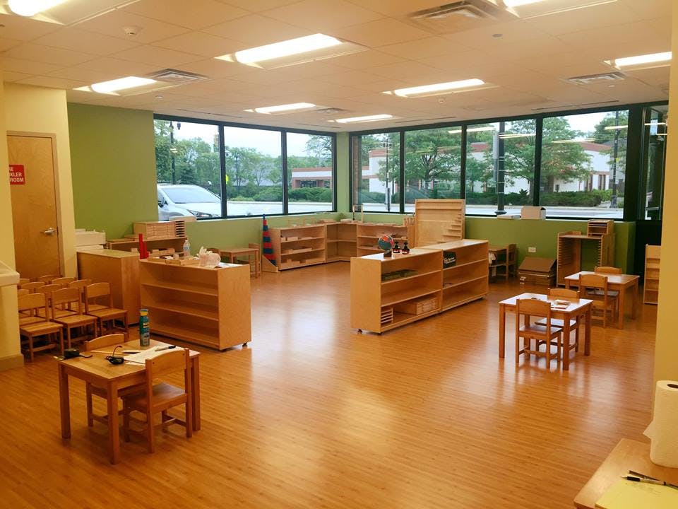 Empty classroom with small tables, chairs, and wooden shelves