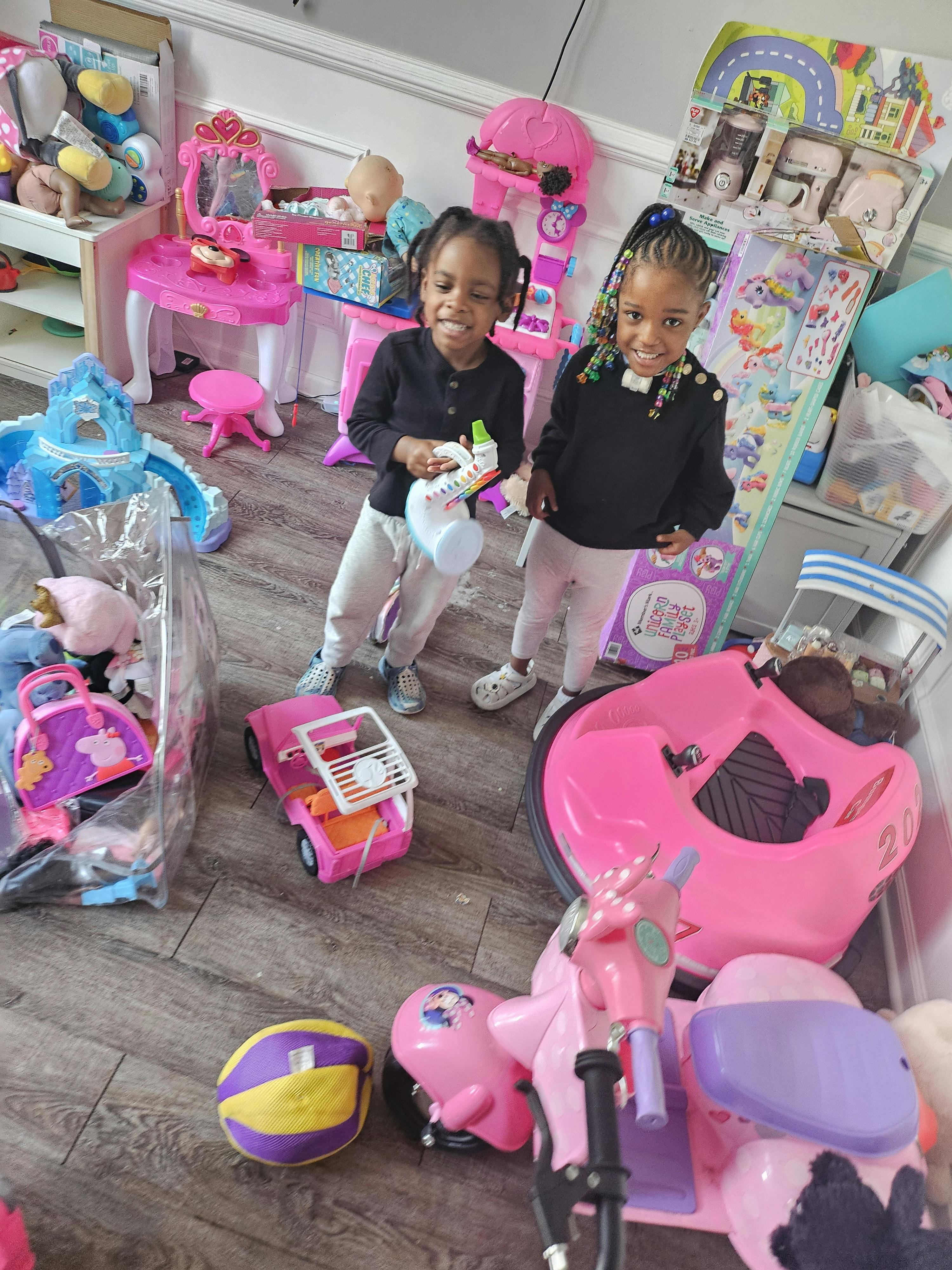 Two children with toys on the floor, one holding a colorful toy saxophone