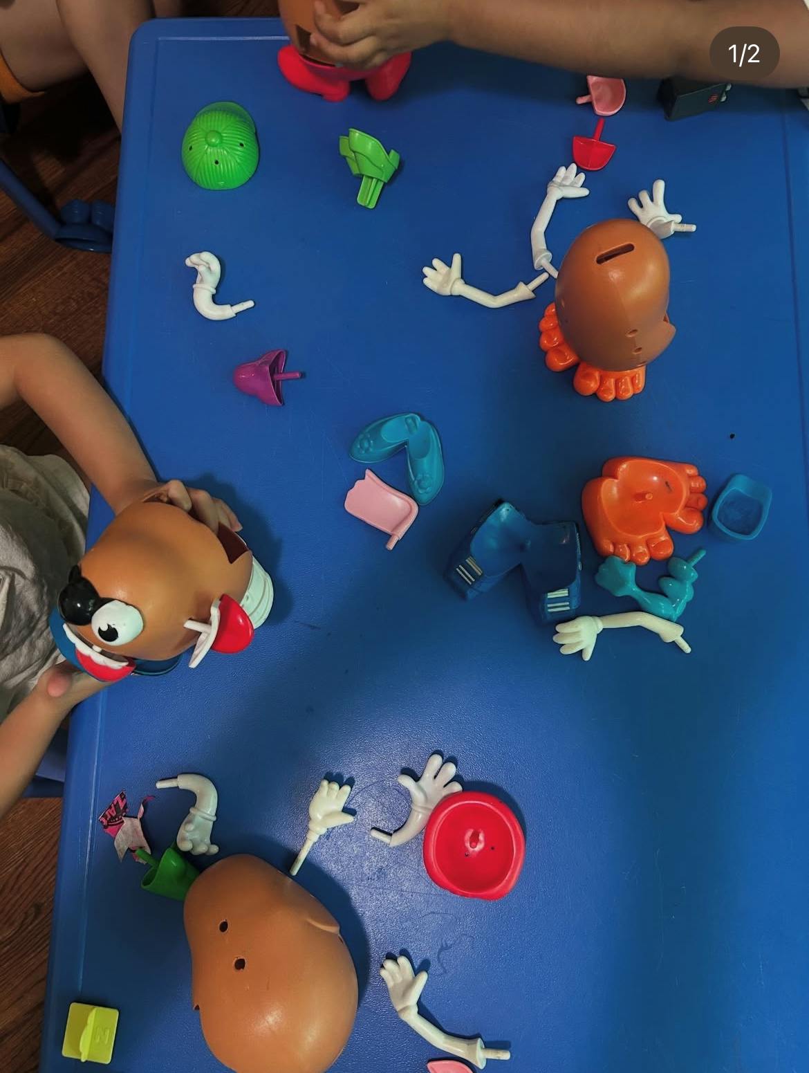 People playing with potato head toys and parts on a blue table