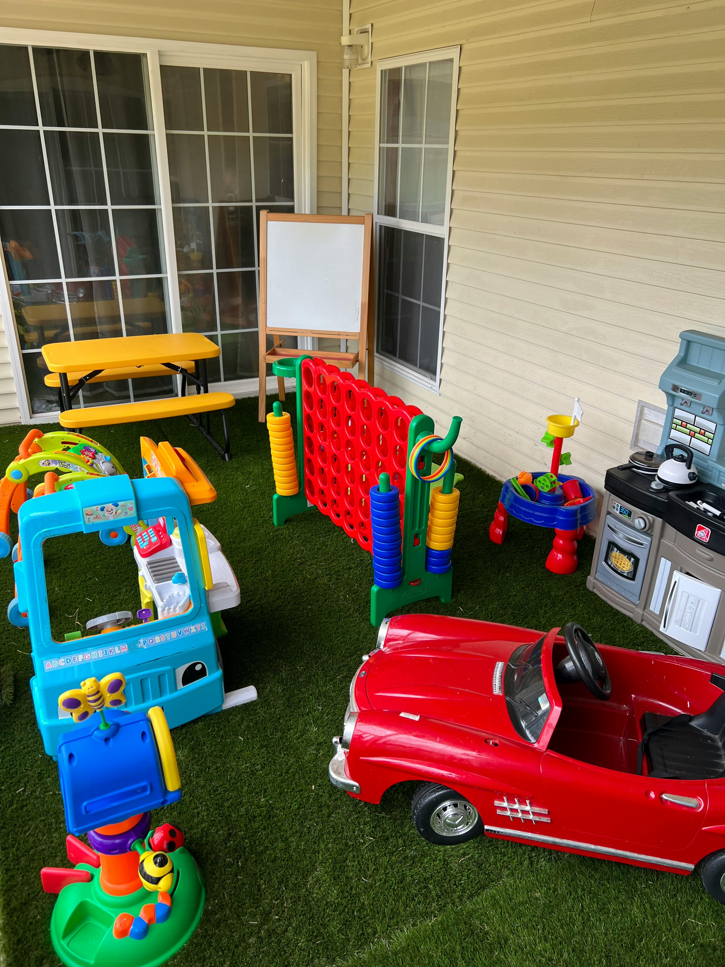 Children's toys including a red car, play kitchen, and large Connect Four game