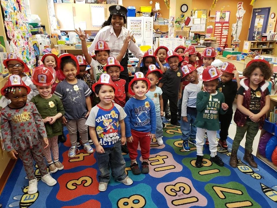 Adult and children in a classroom, children wearing firefighter hats