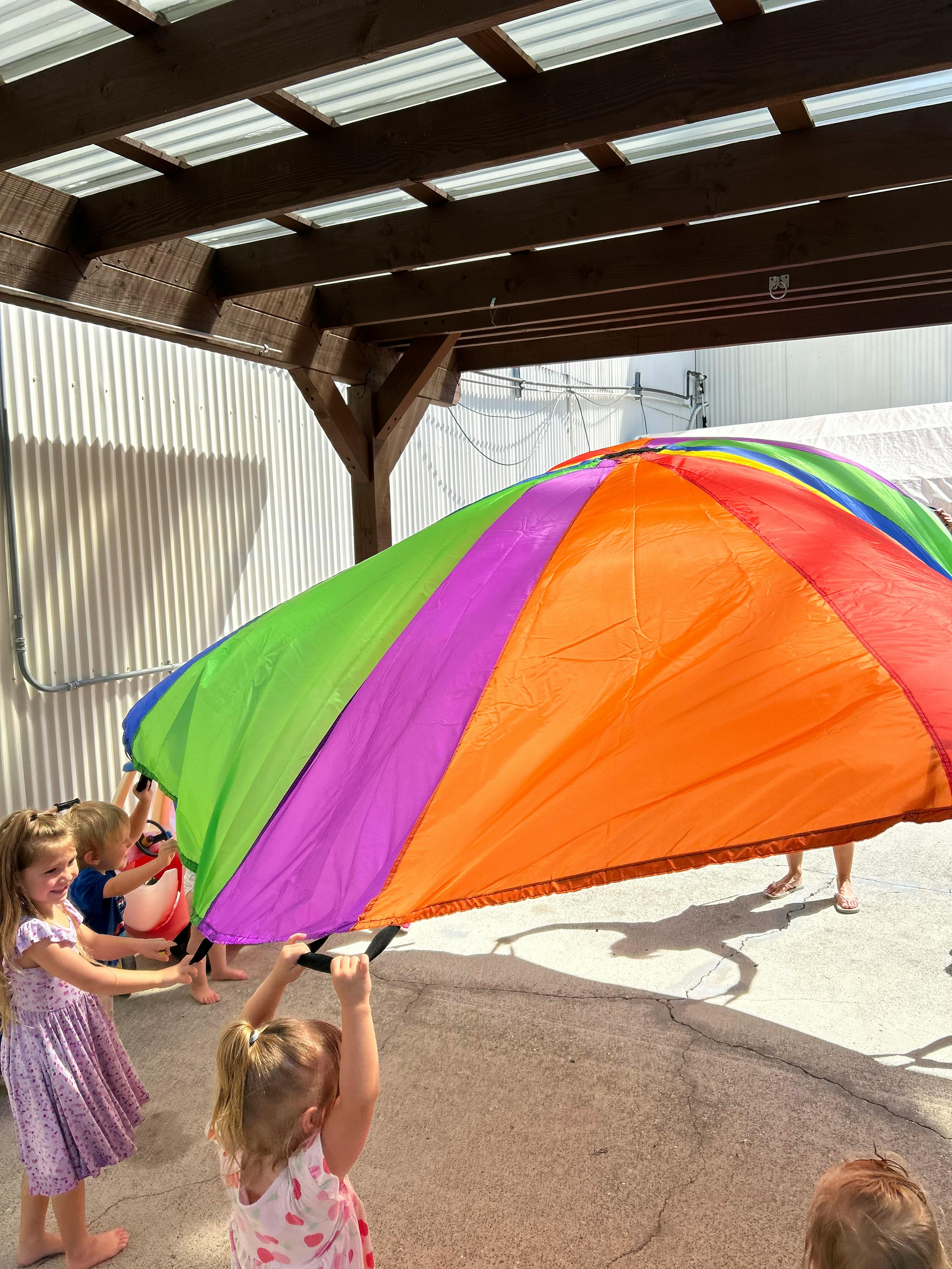Children playing with a large colorful parachute