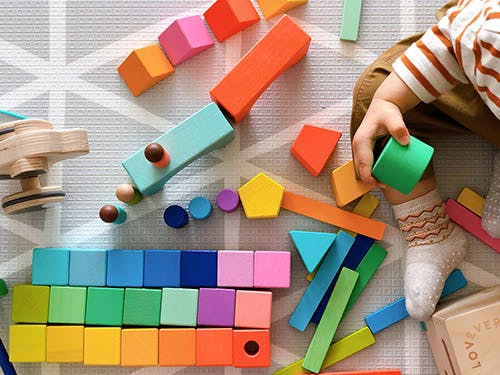Child playing with colorful wooden blocks and shapes on a mat