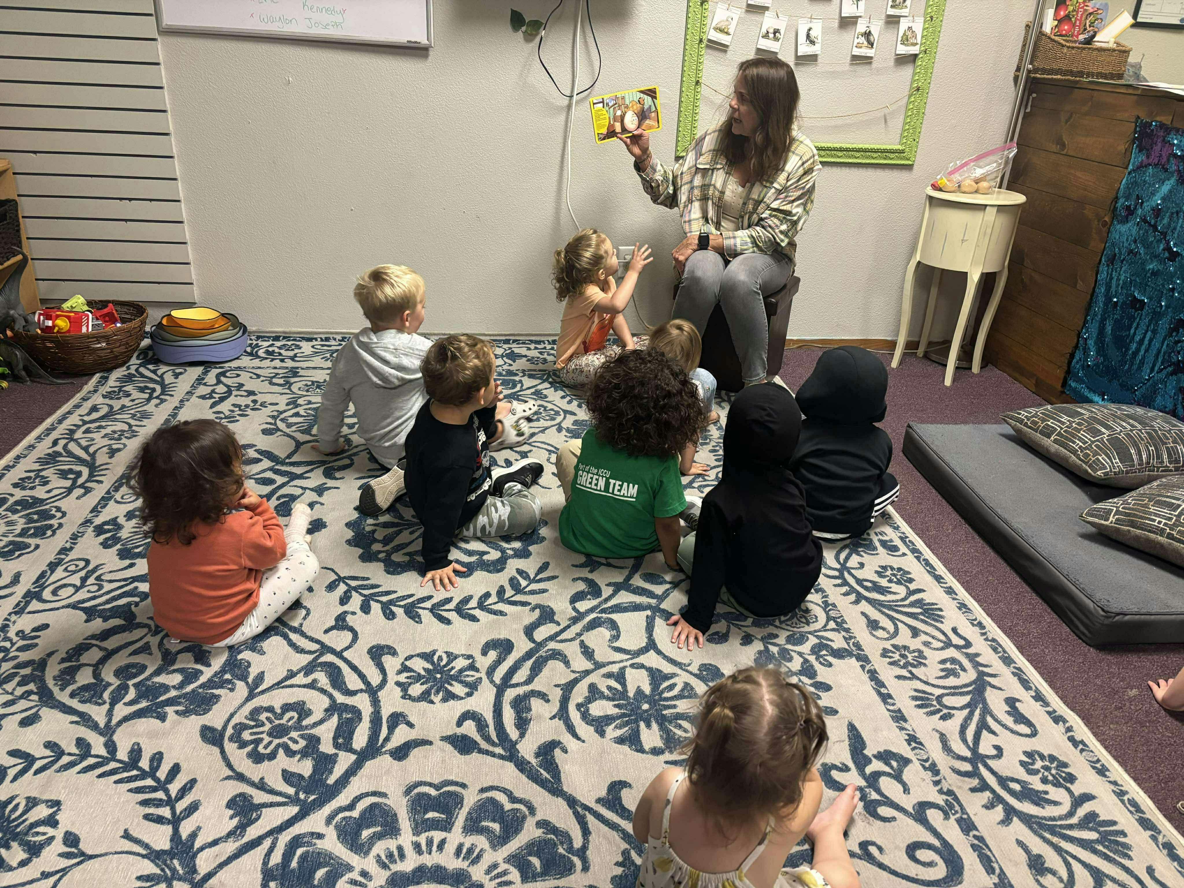 Adult reading a book to a group of children sitting on a rug