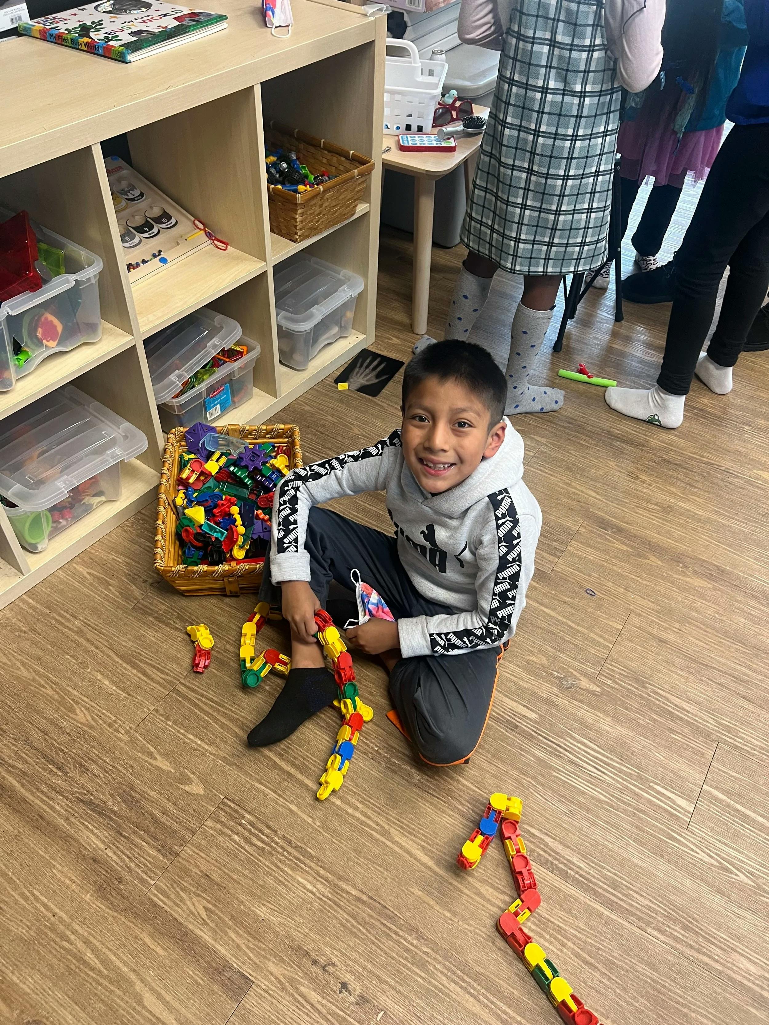 Child smiling while sitting on the floor with colorful construction toys