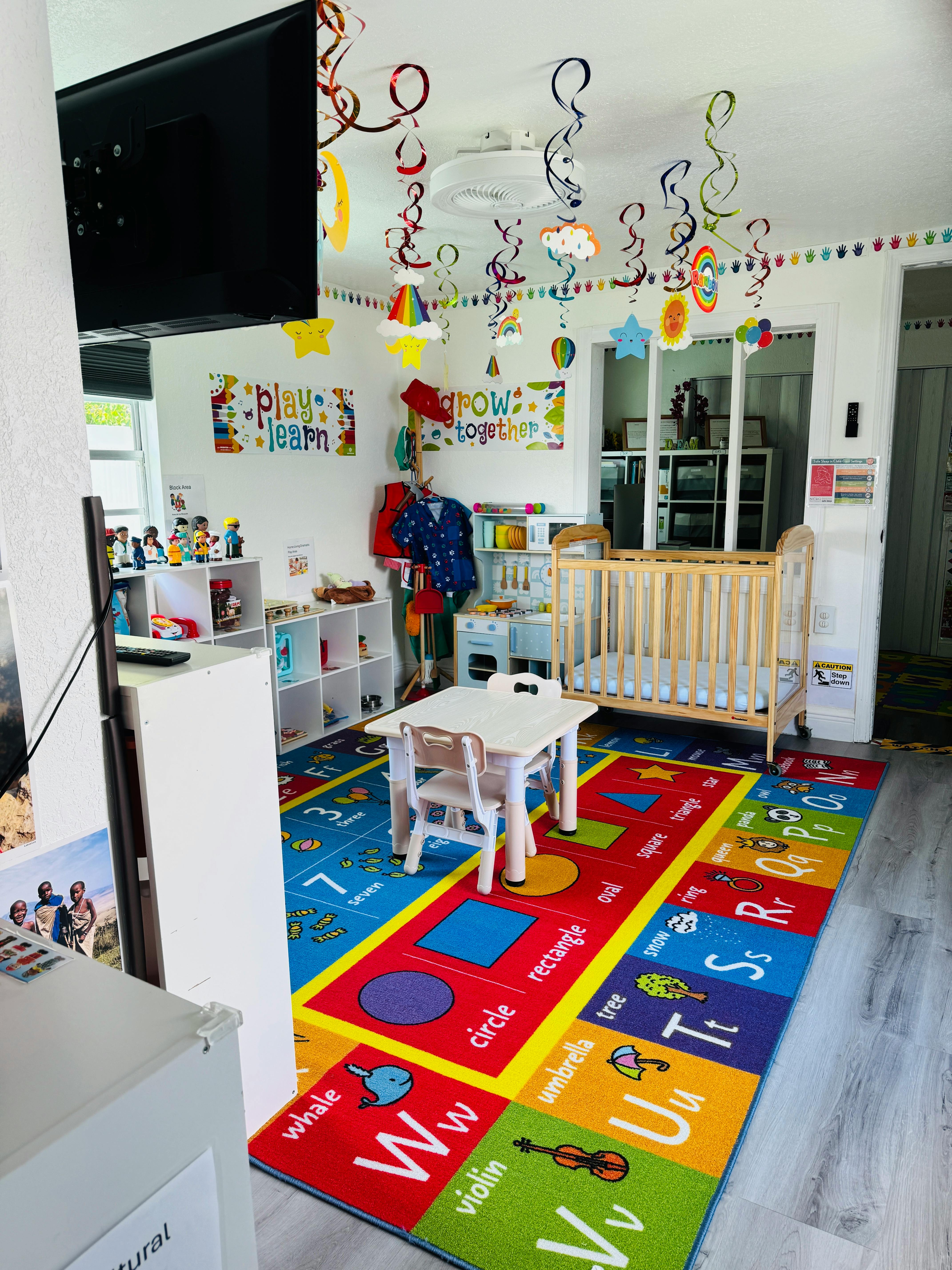 Child's playroom with a colorful alphabet rug, small table, and crib