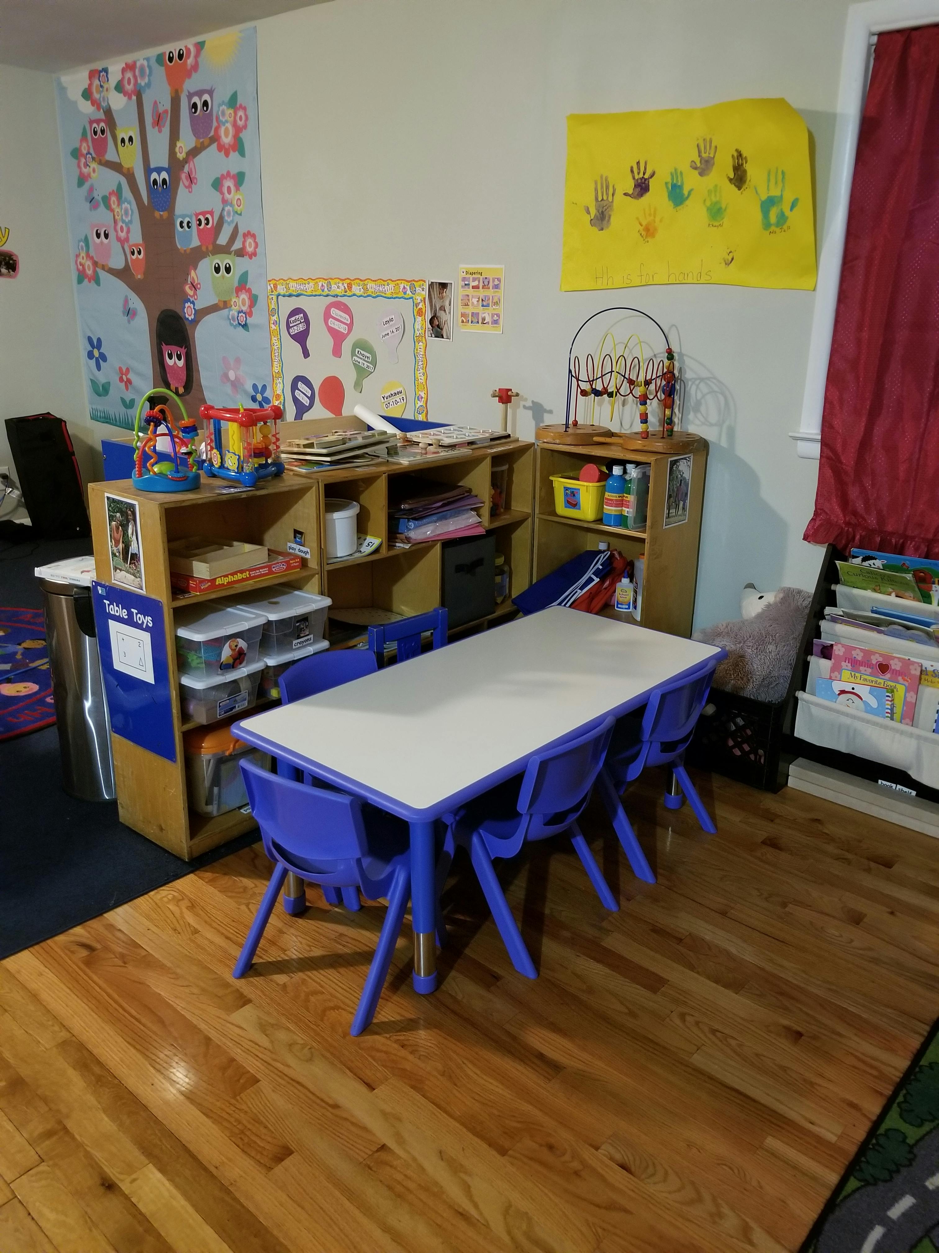 Classroom with small table and chairs, shelves with supplies, and wall decorations
