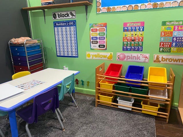 Classroom with a table and chairs, storage unit, and educational posters
